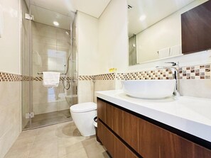 A modern bathroom with a glass shower enclosure, a white sink, and a toilet. - AWS Holiday Homes - Top Retreat near the Burj (Dubai)