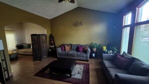 A living room with a ceiling fan, two sofas, a coffee table, and potted plants.