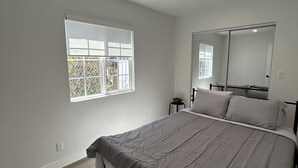 Una camera da letto con un letto, una finestra, uno specchio e una lampada a soffitto.