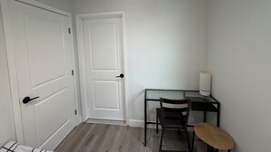 Una stanza con una scrivania, due sedie, una lampada e una porta.