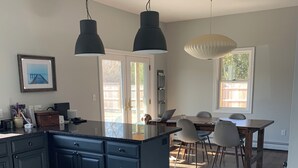 Una cocina moderna con armarios oscuros, una isla central e iluminación colgante.
