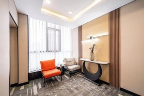 A hotel room with a seating area, a small table, and a decorative wall piece.