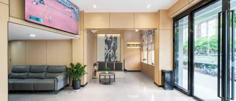 A hotel lobby with a seating area, a television, and a large window.