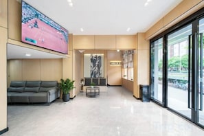 A hotel lobby with a seating area, a television, and a large window.