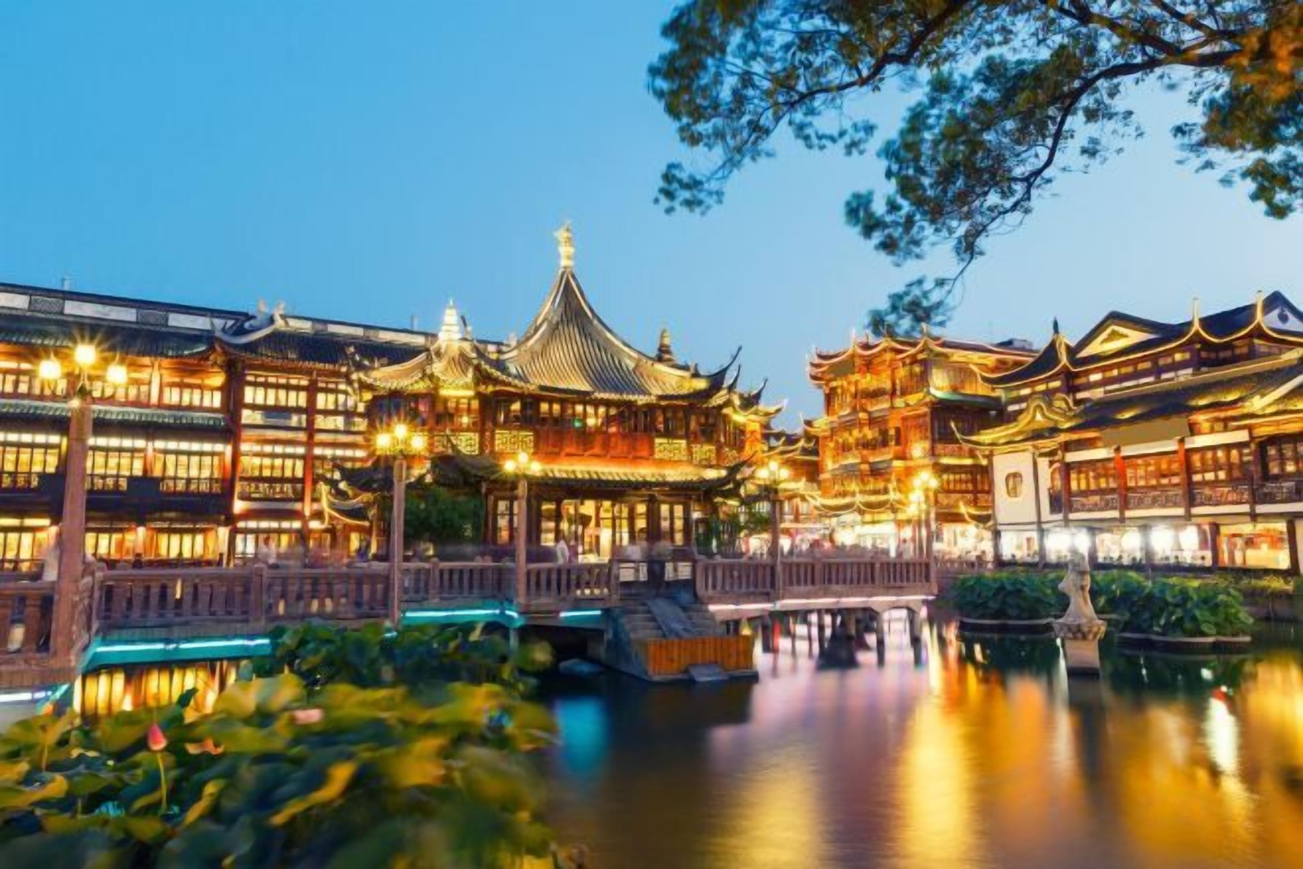 Ein traditionelles chinesisches Gebäude mit einer Brücke über dem Wasser, umgeben von üppigem Grün.