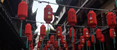 A street with traditional architecture and red lanterns hanging overhead.