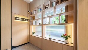 A hallway with wooden paneling, a directional sign, and shelves with decorative items and plants. - GreenTree Inn Express (Shanghai City God's Temple BundYu Garden subway station shop) (Shanghai)