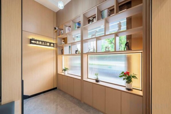A hallway with wooden paneling, a directional sign, and shelves with decorative items and plants.