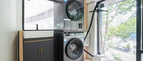 A compact laundry room with a washing machine, dryer, and a vacuum cleaner.