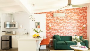 A compact living space with a kitchenette, a green sofa, and a coffee table. - 5 Private Rooms Sleeps 14 Wesley Studio Buyout (Palm Springs)