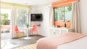 A modern hotel room with a bed, a TV, a small table with chairs, and a window with curtains. - 5 Private Rooms Sleeps 14 Wesley Studio Buyout (Palm Springs)