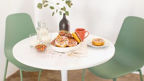 A table with a white tablecloth, two green chairs, a vase with green leaves, a red mug, a glass of milk, a bowl of donuts, and a small bowl of sprinkles. - 5 Private Rooms Sleeps 14 Wesley Studio Buyout (Palm Springs)