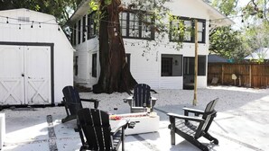 A white house with a large tree, outdoor seating, and string lights. - Walkable Outdoor Oasis BBQ Firepit and Bocce Ball (Tampa)