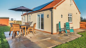 Une maison avec un patio, une table, des chaises et une antenne parabolique.