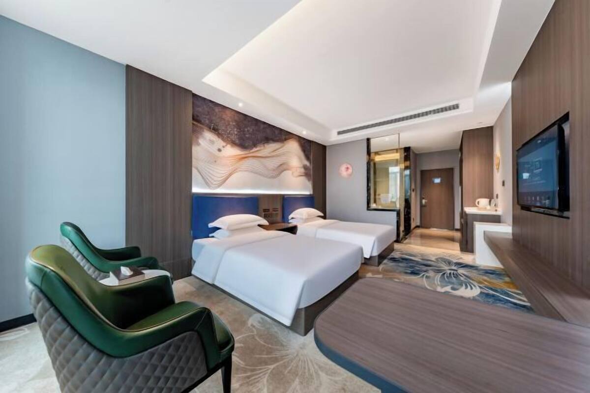 Une chambre d’hôtel comprenant un lit, deux tables de chevet, une télévision, un bureau et une chaise.
