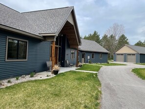 A residential building with a sloped roof, a front porch, and a driveway leading to a garage.
