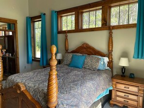 A bedroom with a four-poster bed, a nightstand, and a dresser.