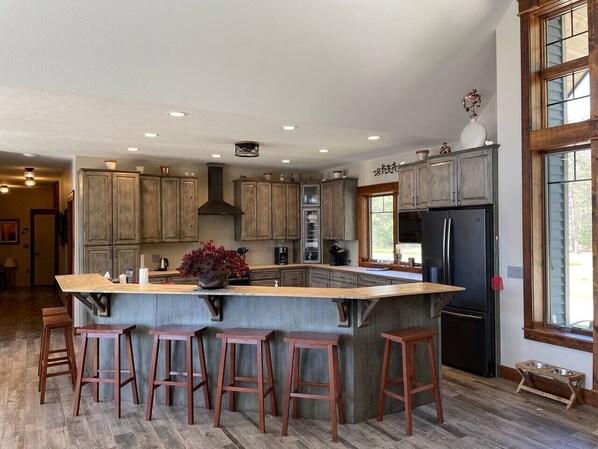 A spacious kitchen with a large island, wooden bar stools, and a built-in refrigerator.