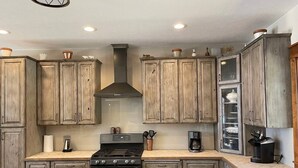 Una cocina con armarios de madera, estufa y cafetera.