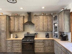 A kitchen with wooden cabinets, a stove, and a coffee maker.