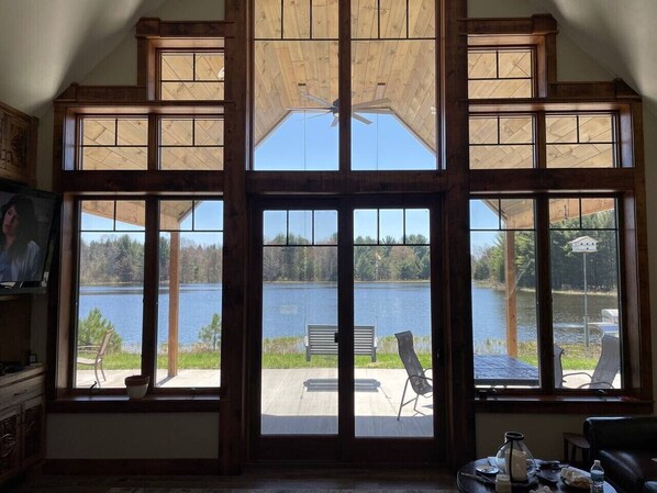 A room with large windows overlooking a lake, a ceiling fan, and a dining table with chairs.