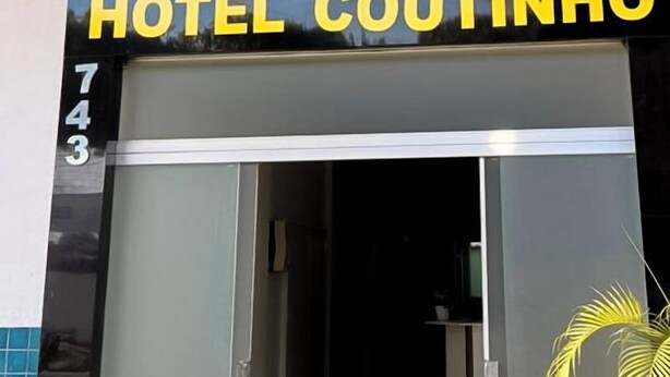 The entrance to Hotel Coutinho with a glass door and a balcony above. - Hotel Coutinho PIO XII (Pirapora)