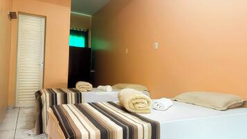 Habitación de hotel con dos camas, ropa de cama a rayas y toallas.