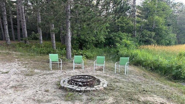 A campsite with a fire pit and four green chairs arranged around it. - Woodsy and Private- Rustic Cabin (Paradise)
