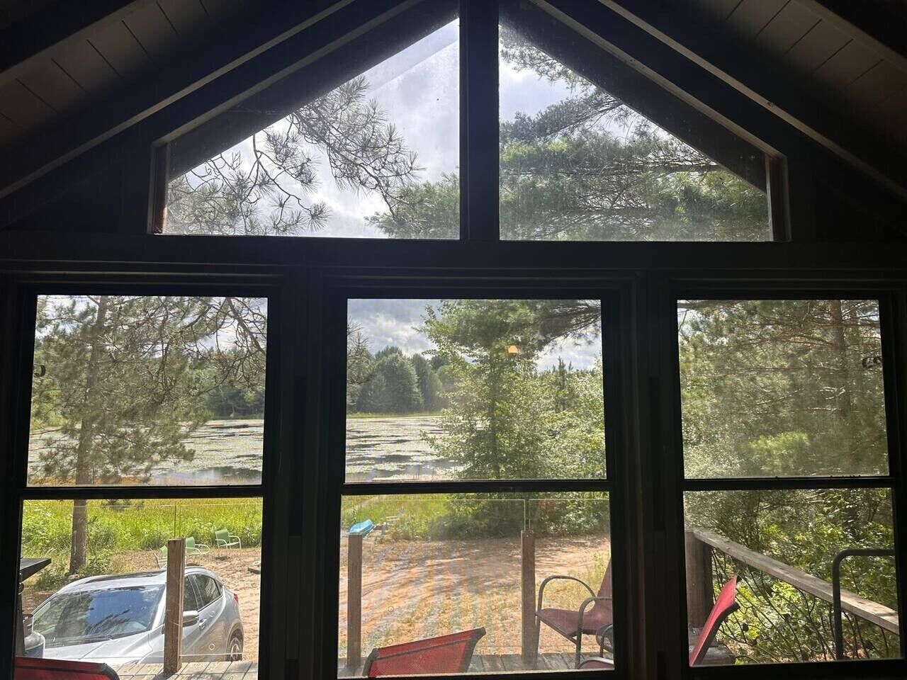 A room with a large window overlooking a natural landscape, including a body of water and trees.