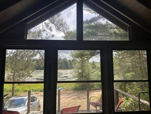 A room with a large window overlooking a natural landscape, including a body of water and trees.