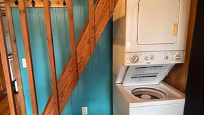 A laundry room with a washing machine and dryer, wooden beams, and a teal wall. - Woodsy and Private- Rustic Cabin (Paradise)