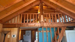 A wooden interior with a high ceiling, a balcony, and a staircase. - Woodsy and Private- Rustic Cabin (Paradise)