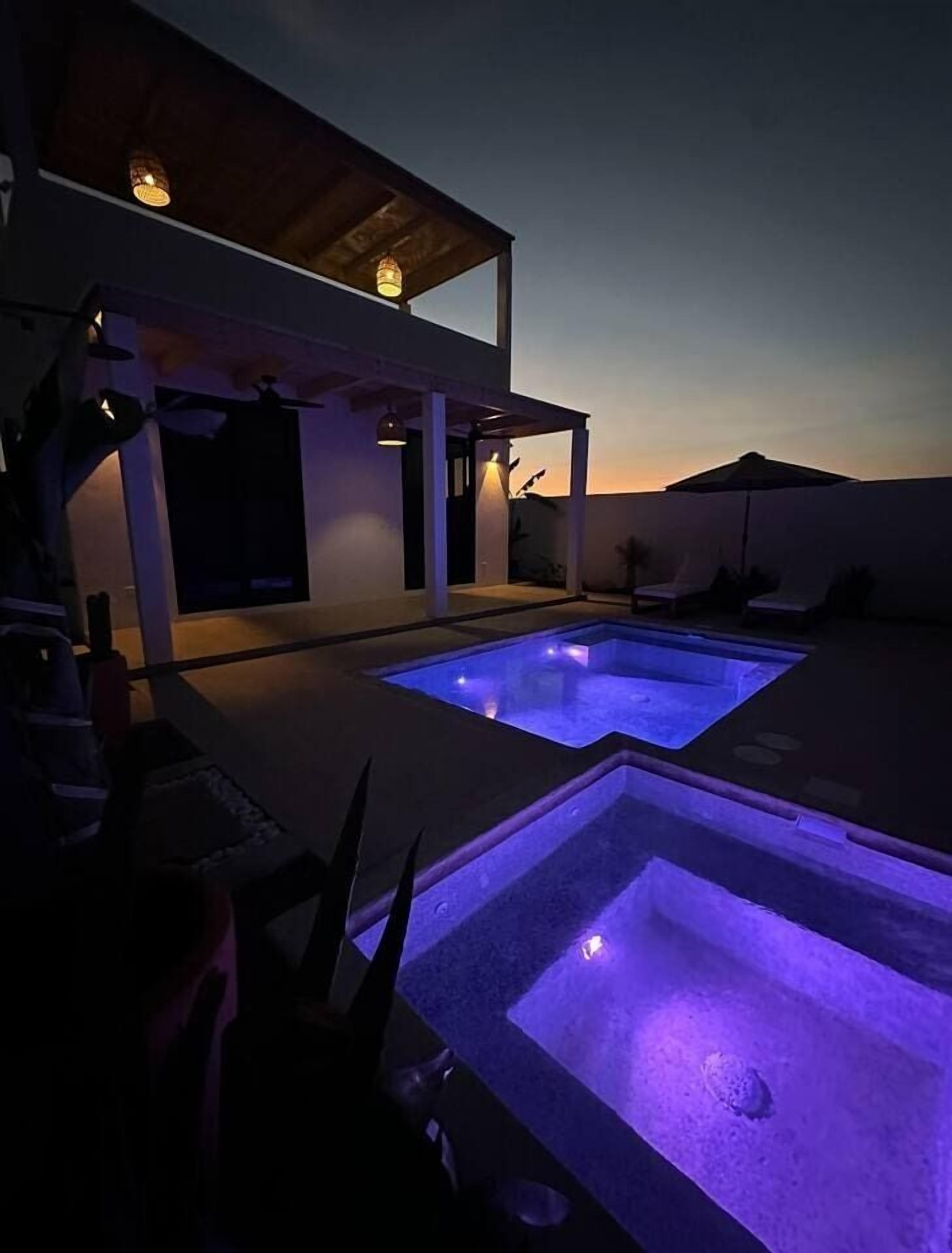 A pool area with two rectangular pools, one with a blue light.
