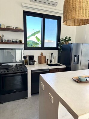 Une cuisine moderne équipée d’une cuisinière à gaz, d’un lave-vaisselle et d’un réfrigérateur en acier inoxydable.