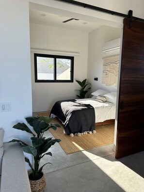 Une chambre à coucher moderne avec un lit, une fenêtre et une grande plante.