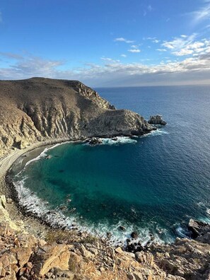 Un paisaje costero con terreno rocoso y mar azul cristalino.