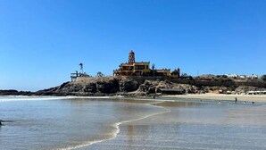 A coastal building with a dome on top, situated on a rocky outcrop near a sandy beach. - Casa Cielo | Private Luxury with Ocean Views (El Pescadero)
