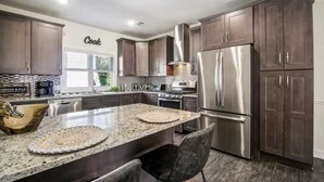 A modern kitchen with dark wood cabinets, stainless steel appliances, and a granite countertop. - Saddle Ridge at Kearny - Luxury 4-Bedroom Oasis (Kearny)