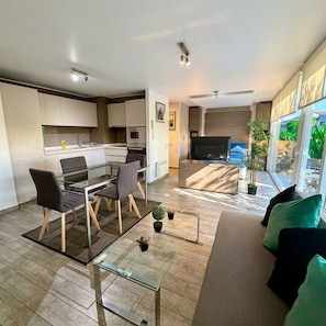 A modern living space with a dining area, kitchen, and a TV in the living room. - Lindo estudio a pasos del Metro Los Dominicos (Santiago)