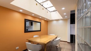 A conference room with a wooden table, white chairs, a large mirror, and a skylight. - Family house in the north of Bogota (Bogotá, D.C.)