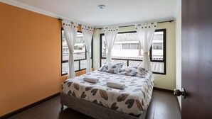 A bedroom with a bed, curtains, and a view of the outside. - Family house in the north of Bogota (Bogotá, D.C.)