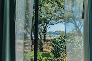 Une vue à travers une fenêtre donnant sur une plage et des arbres.
