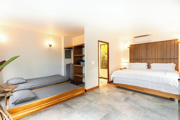 Een kleine kamer met een bed, een zithoekje en een kledingkast.