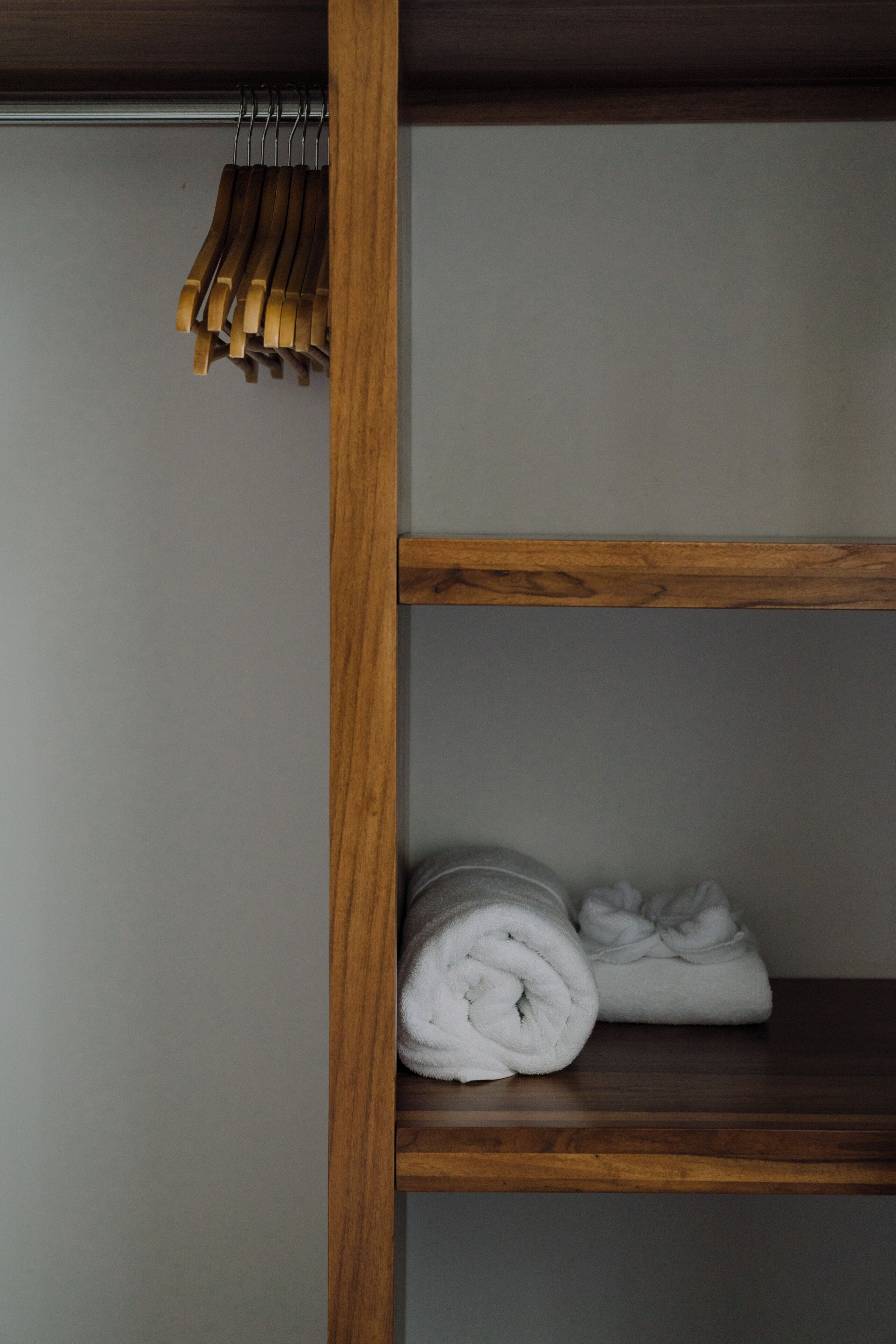 A wooden shelf with a rolled white towel.