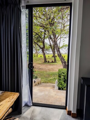 Una habitación con un amplio ventanal corredero que da a un espacio exterior con árboles y césped.