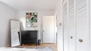 A bedroom with a bed, a dresser, a door, and a closet.