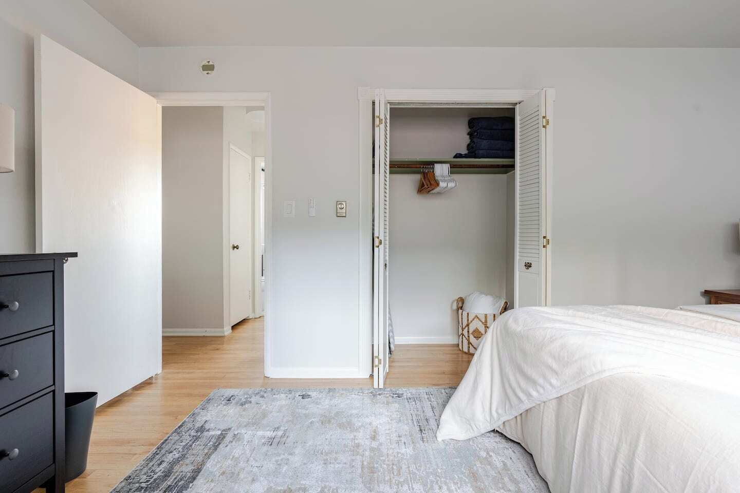 A bedroom with a bed, a dresser, a closet, and a hallway.