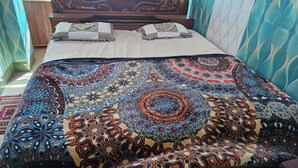Una cama con una colcha estampada, un cabecero de madera y una mesita de noche con una botella.