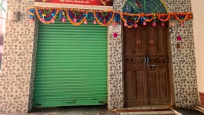 Un escaparate con un persiano verde, una puerta de madera y un cartel que anuncia ropa y menaje del hogar GARANZA.