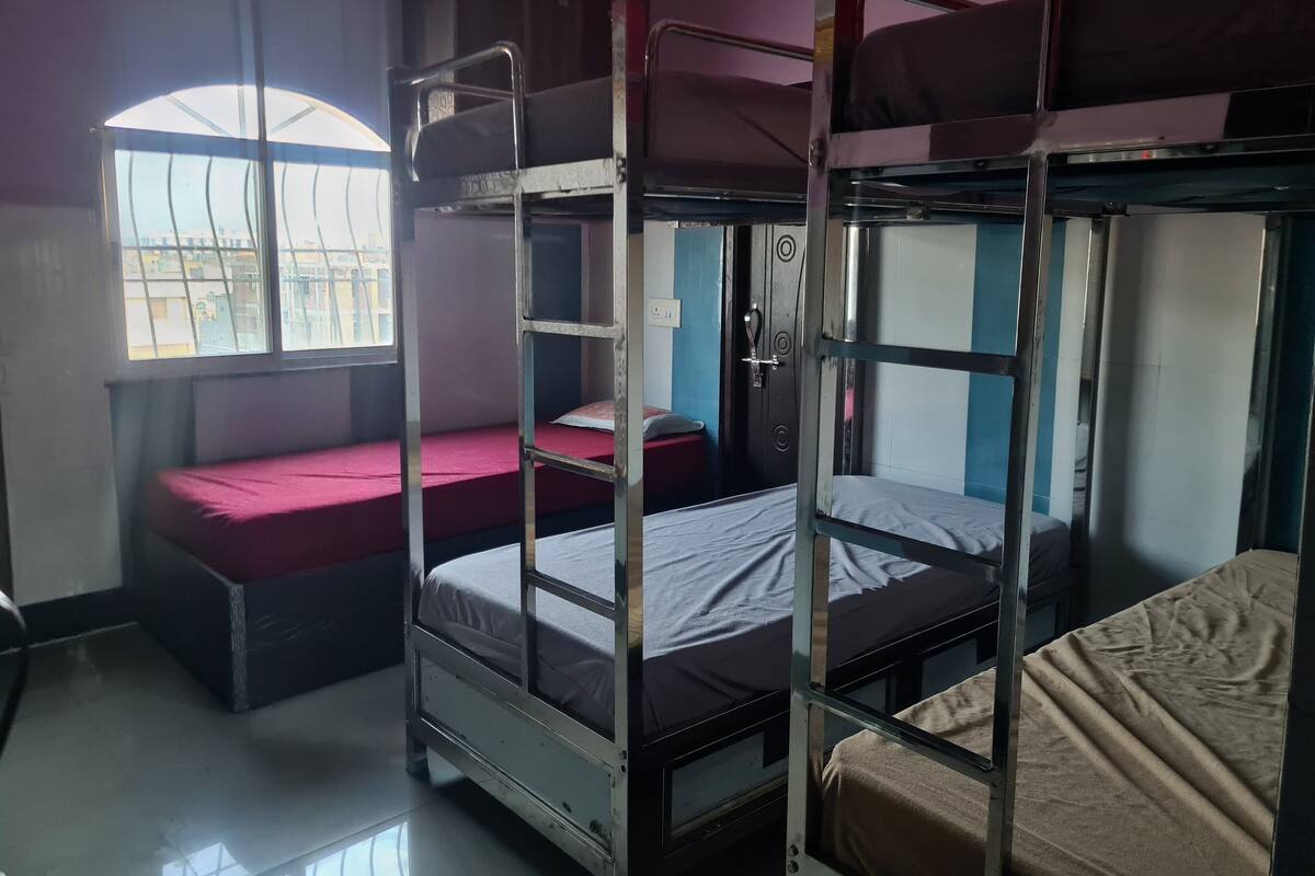 A dormitory room with bunk beds, a window, and a door.